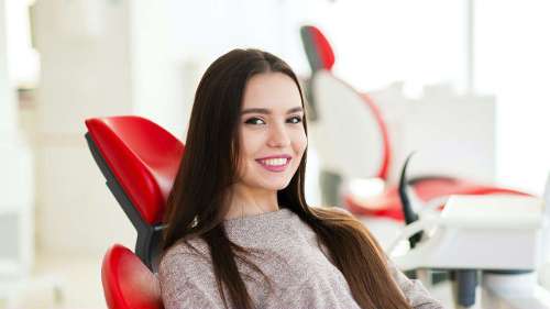 A woman smiling confidently while sitting in a dental chair