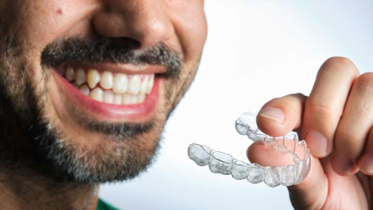 A patient holding aligners in Bastrop,TX
